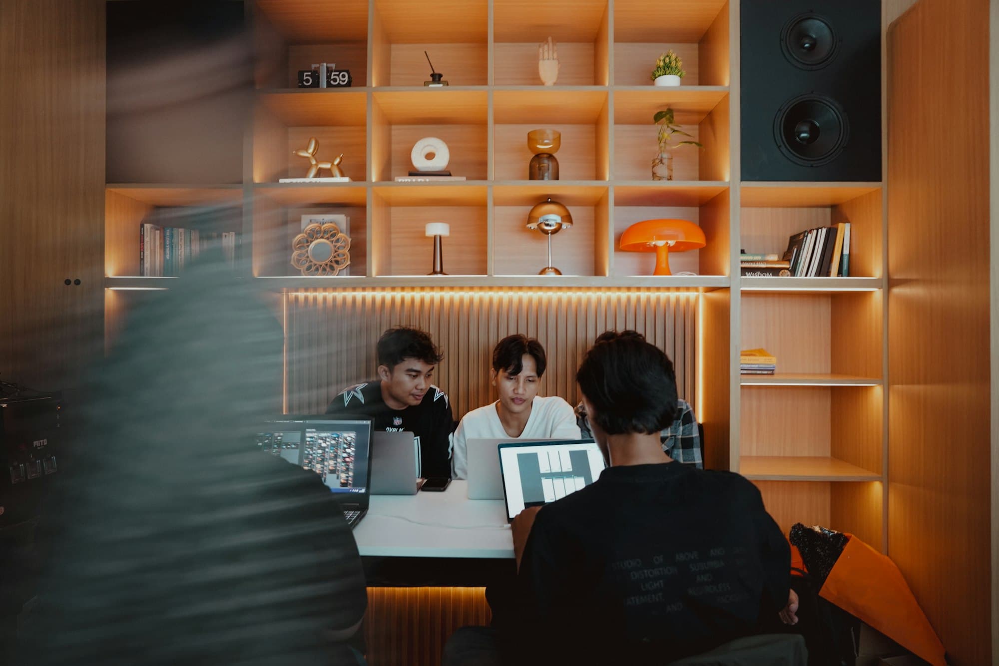 A small team collaborating at their computers in a warmly lit studio