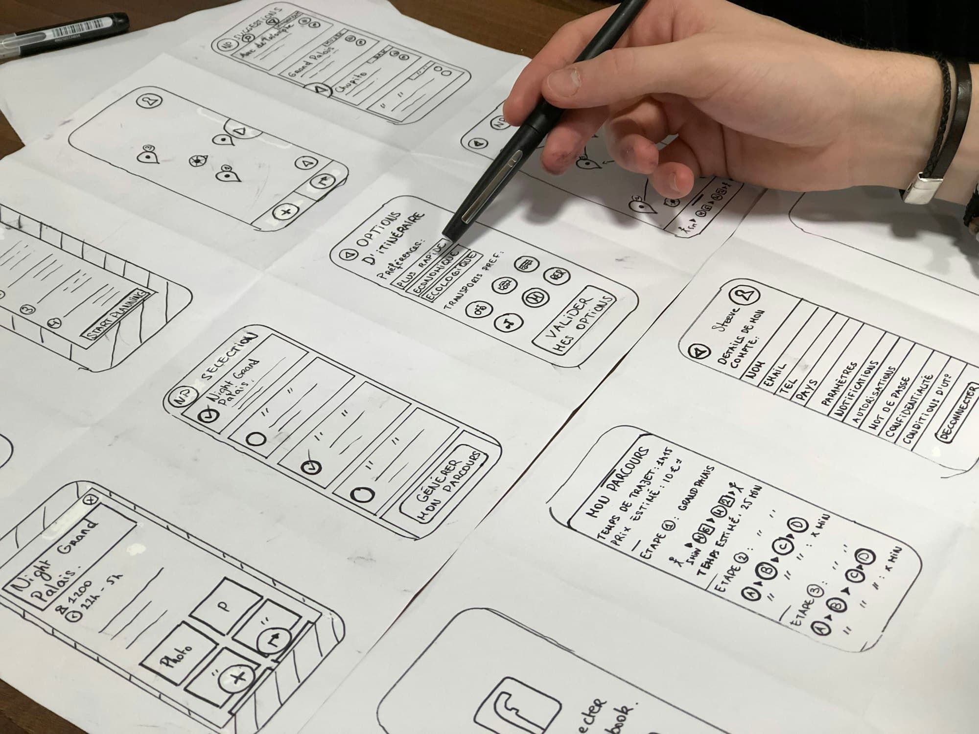 Hands sketching mobile app screens on paper