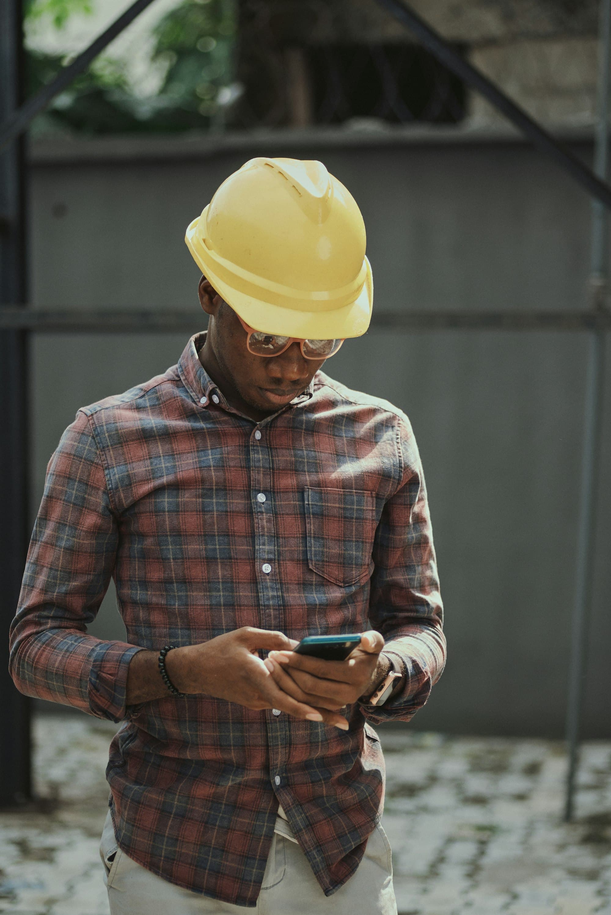 A contractor in a hard hat checking his smartphone on a job site