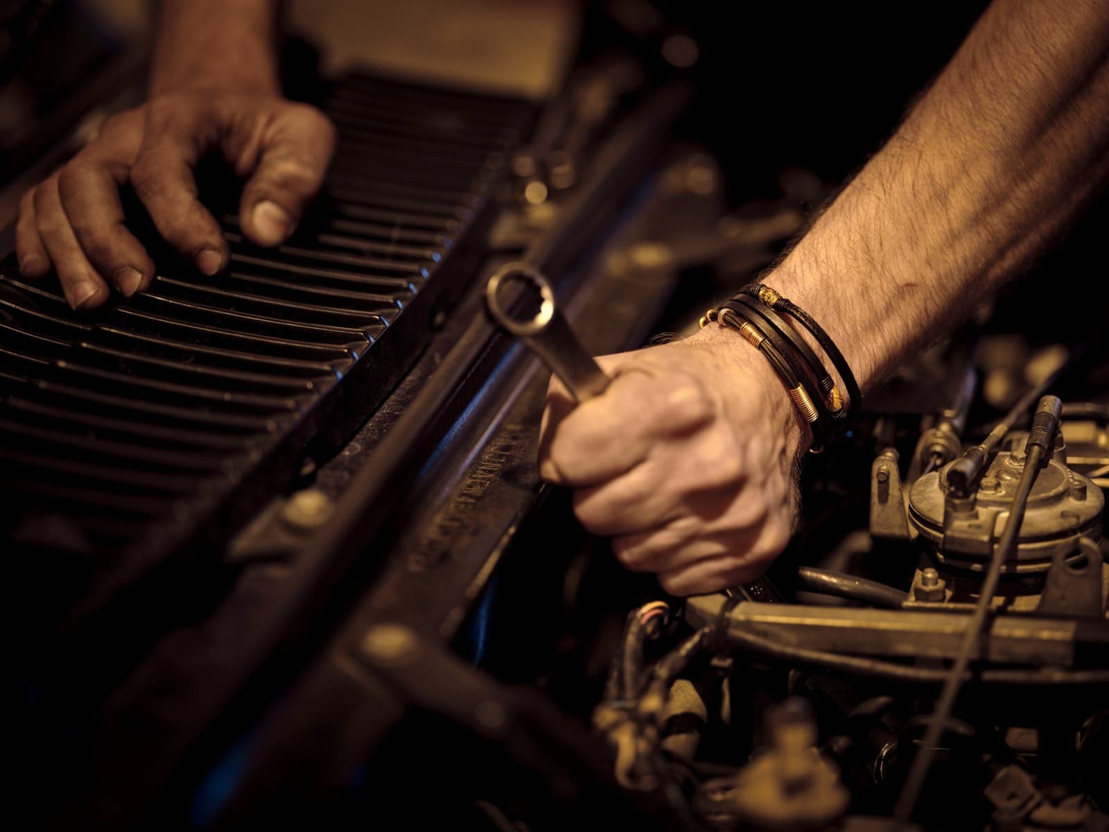 A mechanic's hands working on a car engine with a wrench