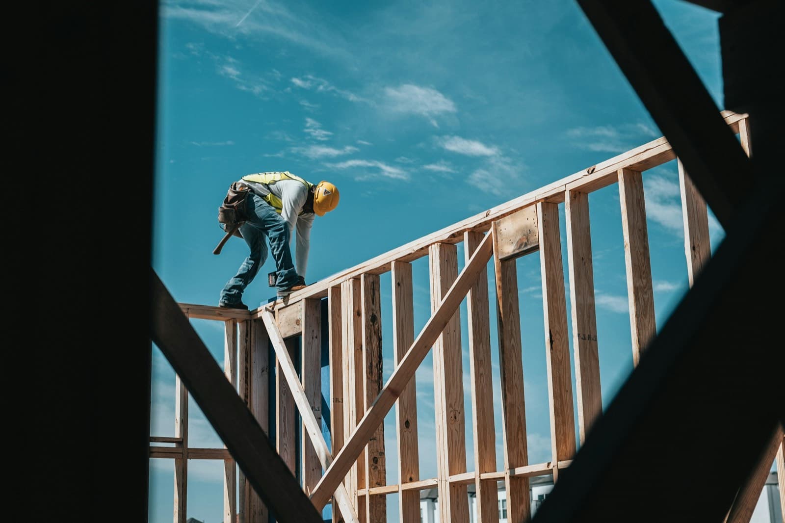 A construction worker in a hard hat on a timber frame