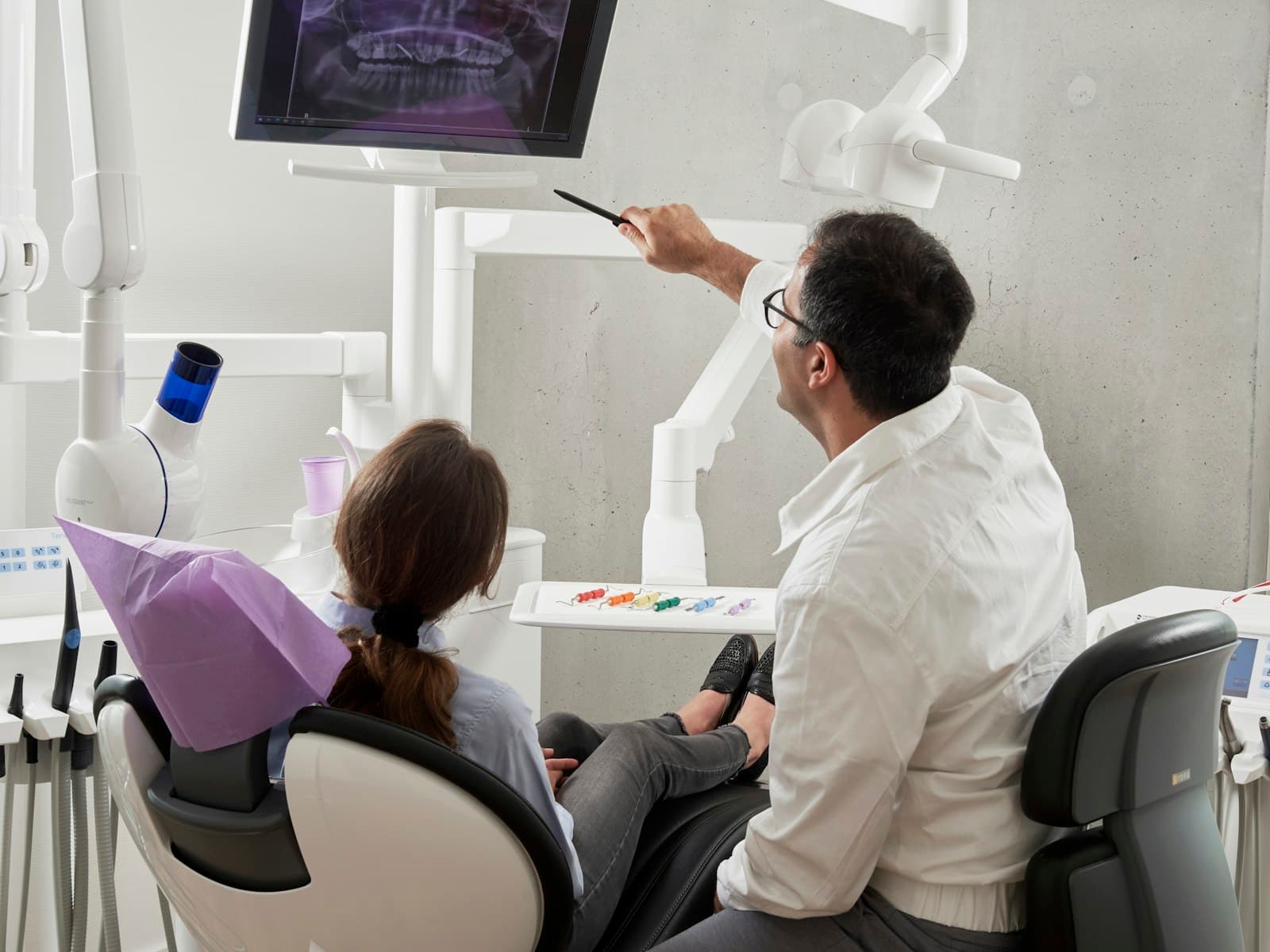 A dentist explaining treatment to a patient in the chair