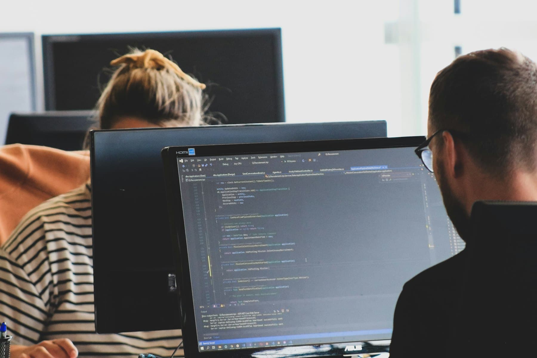 Two developers reviewing code together at their monitors